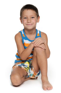 genç oğlan beyaz zemin üzerine oturuyor