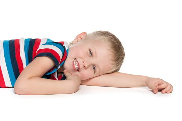 Glücklicher blonder Junge liegt auf dem weißen — Stockfoto