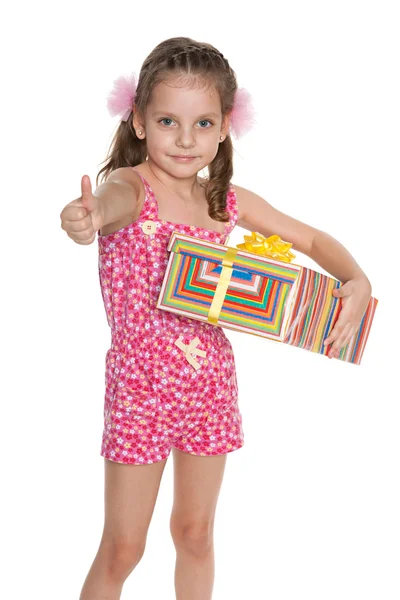 Little girl with a gift box holds her thumb up — Stock Photo, Image