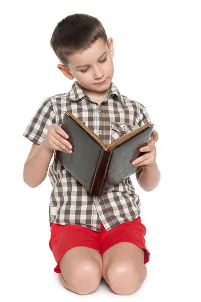 Young boy reads an old book — Stock Photo, Image