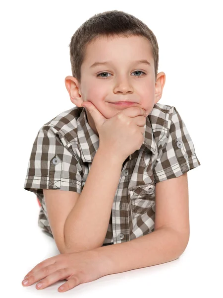 Cute pensive boy is lying on the white — Stock Photo, Image