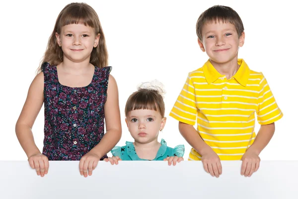 Lachende kinderen houden een wit vel papier — Stockfoto