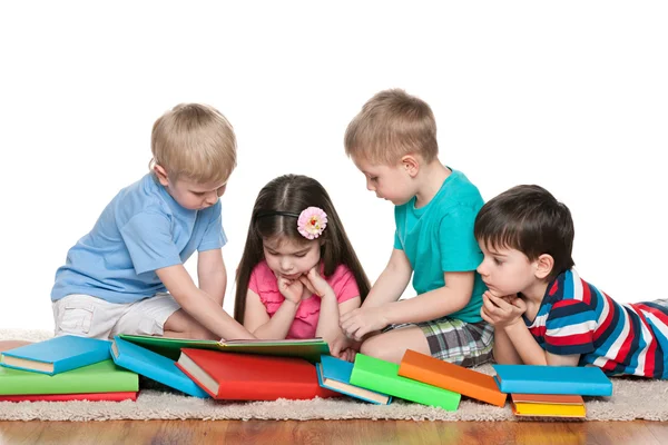 Vier kinderen met boeken op de verdieping — Stockfoto