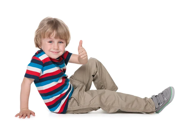 Niño pequeño en el suelo sostiene su pulgar hacia arriba — Foto de Stock