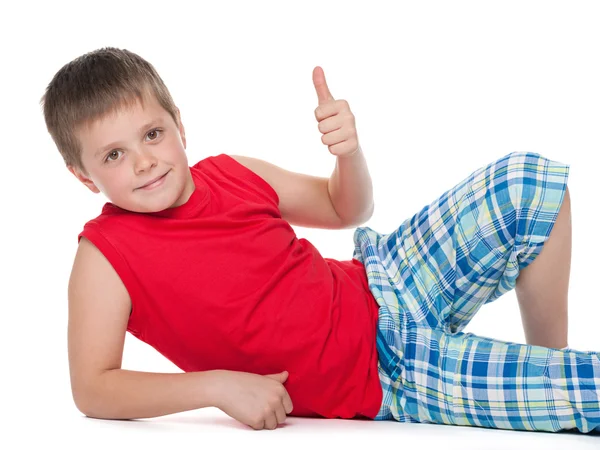 Young boy on the floor holds his thumb up — Stock Photo, Image