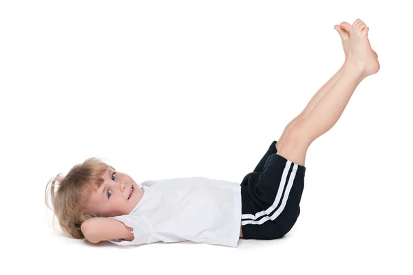 Lachende jongetje voert gymnastische oefeningen — Stockfoto