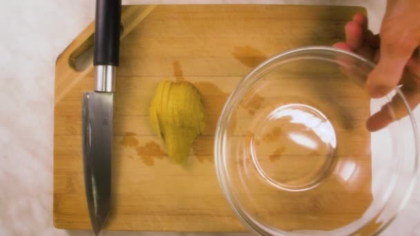 女性の手は透明サラダボウルにキッチンボードからスライス梨を入れ — ストック動画