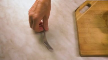 Bir kadının eli bir çatalı alır ve dilimlenmiş meyvelerle dolu cam bir kaba koyar. Meyve salatası..