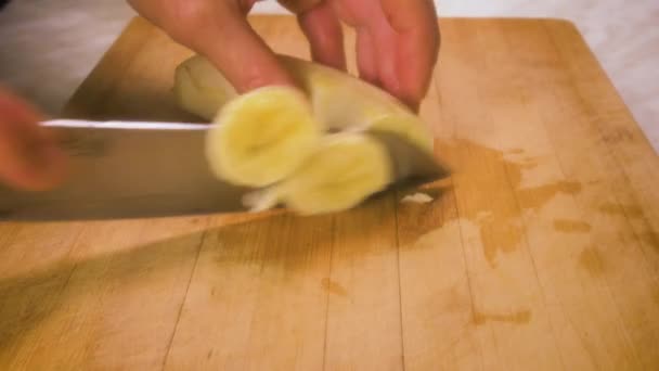 Χέρια Των Γυναικών Κόβουν Μια Μπανάνα Ένα Μαχαίρι Στον Πίνακα — Αρχείο Βίντεο