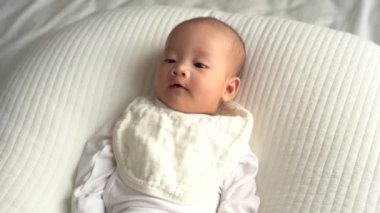 Beyaz yastığın üzerinde yatan sevimli gülümseyen bebeğin 4K görüntüsü 