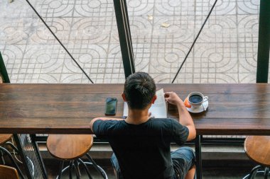 Asyalı adam sabah kitap okuyor.