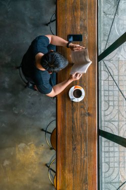 Asyalı adam kitap okuma ve kahve içme