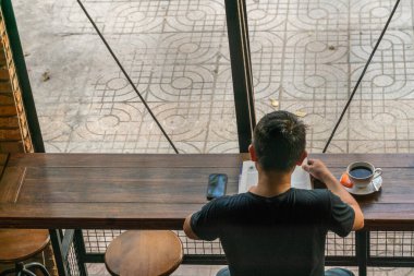 Asyalı adam kahve dükkanında bir kitap okudu.