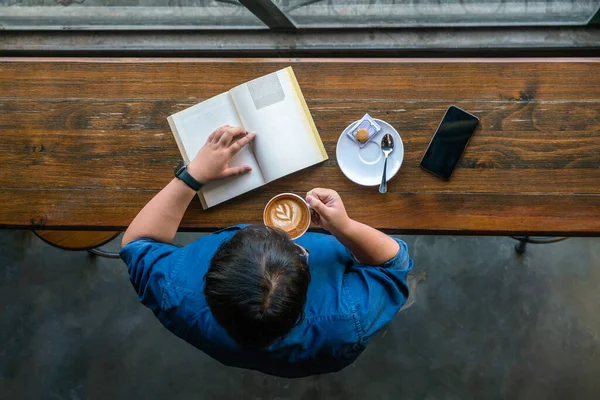 Draufsicht auf ein junges Mädchen, das Kaffee trinkt und Buch liest — Stockfoto