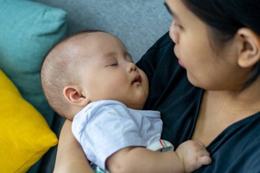 Güzel bebek annesinin elinde uyuyor.