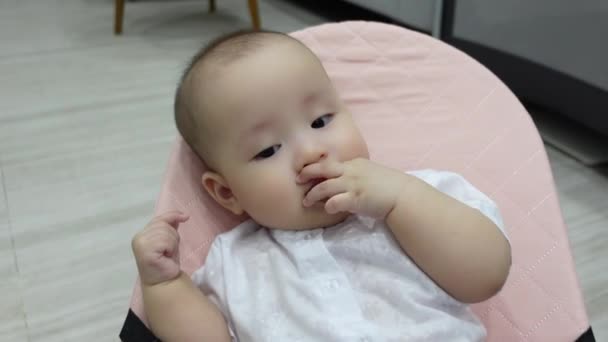 Ασιατική χαριτωμένο κοριτσάκι κάθεται και πιπίλισμα δάχτυλα — Αρχείο Βίντεο