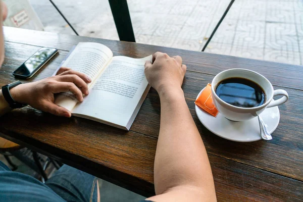 Mężczyzna czyta książki i pije kawę rano. — Zdjęcie stockowe