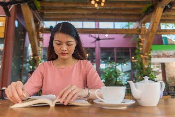 Hermosa mujer joven asiática leyendo libro en casa Imagen De Stock
