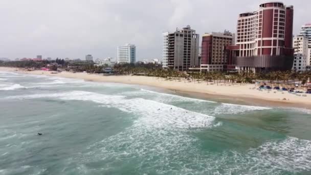 Vackra vågor i havet, imponerande vit sandstrand och byggnader flygfoto på en lugn sommardag. — Stockvideo