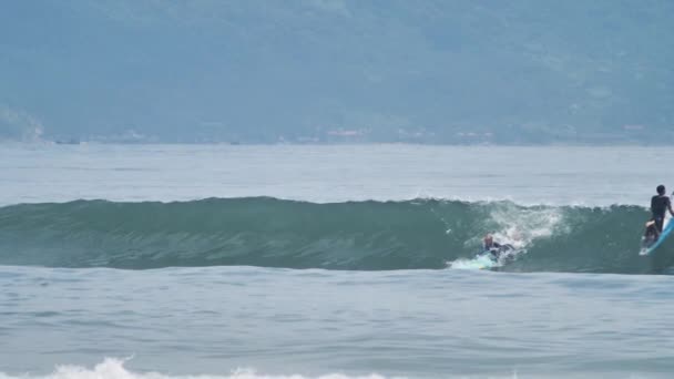 Barevná vlna v modrém moři naráží na surfaře za slunečného dne. — Stock video