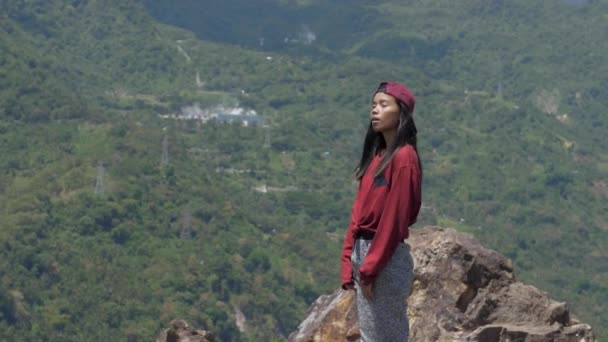 Asiatisk ung kvinna tittar på berget och ser sig omkring i Asien, reser genom djungeln bland palmer i soligt väder — Stockvideo