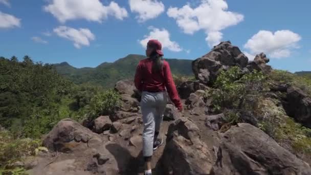 Mulher jovem asiática sobe uma montanha na Ásia, viaja pela selva entre palmeiras em tempo ensolarado — Vídeo de Stock