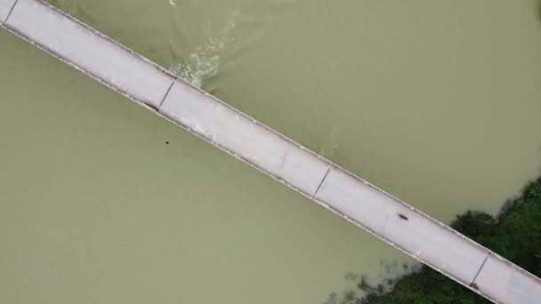 Luftaufnahme einer Brücke mit Straße, einer Motorradfahrt, einem stürmischen Fluss unter der Brücke — Stockvideo