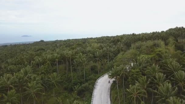 Man riding scooter through jungles. Aerial View of A Young Man Riding a Moped on a Mountain Road in the Forest — Stock Video