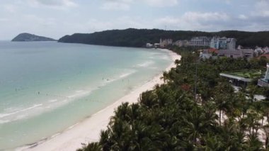 Beyaz Kum ve Asya 'da bir tatil köyünde sahil boyunca uzanan Palmiye ağaçlarının olduğu bir adada Mavi Okyanus manzarası.