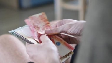 Parlak bir odada erkekler para sayar Filipin pesoları ve diğer para birimleri