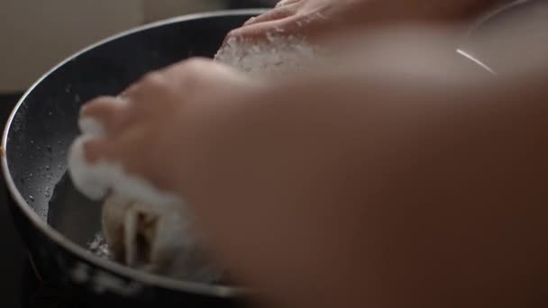 Le mani delle donne tengono un petto di pollo in farina e lo mettono su una padella bollente sul tavolo della cucina, preparando una deliziosa cena. — Video Stock