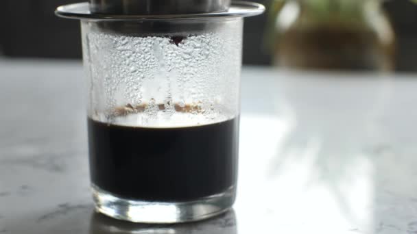 Gros plan d'un verre transparent debout sur la table, goutte à goutte de café — Video