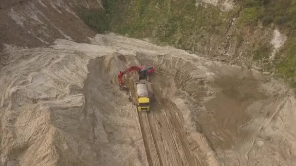 De graafmachine laadt het zand in de vuilniswagen. Mijnbouw truck vervoeren de mineralen in de zandgroeve. Luchtfoto van een open mijnbouw. — Stockvideo
