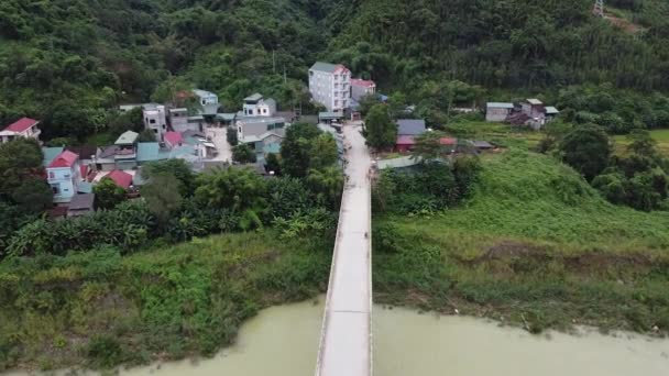 Вид з повітря на село біля річки, навкруги гір і лісу — стокове відео