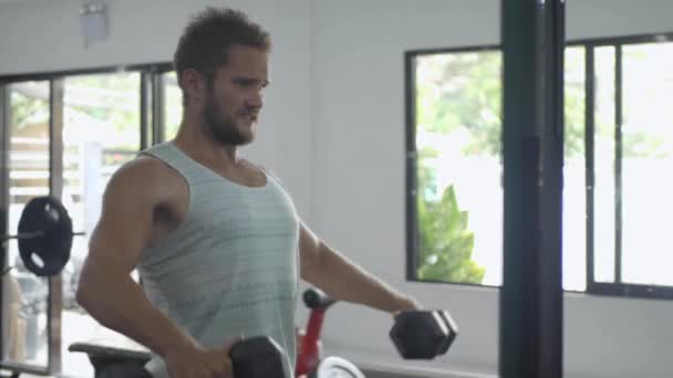 Ένας νεαρός Ευρωπαίος πάει για αθλητισμό, κάνει ασκήσεις με αλτήρες στο γυμναστήριο — Αρχείο Βίντεο