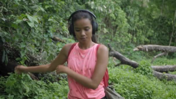 Bela viagem mulher asiática desfrutar de andar e ouvir música de fone de ouvido no acampamento floresta fundo com alegria e felicidade — Vídeo de Stock