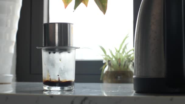 Nærbilde av et gjennomsiktig glass som står på bordet og drypper kaffedråpe for dråpe. – stockvideo