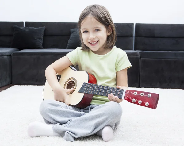 Bambina con chitarra seduta sul pavimento — Foto Stock