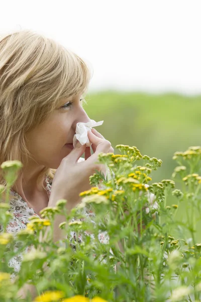 Woman blowing nose into tissue outdoors — Stock Photo, Image