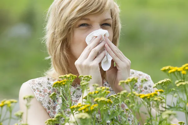 Woman blowing nose into tissue outdoors — Stock Photo, Image