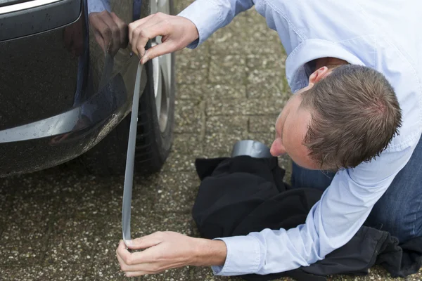 Homme utilisant la bande de conduit pour réparer la voiture . — Photo