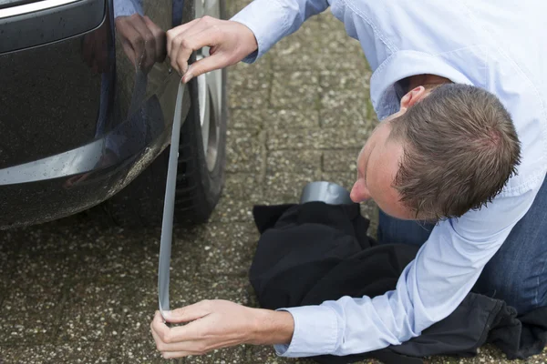 Muž opravit auto pomocí lepicí pásky. — Stock fotografie