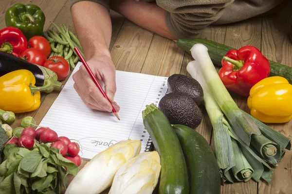 Man's hand writing list of organic vegetables — Stock Photo, Image