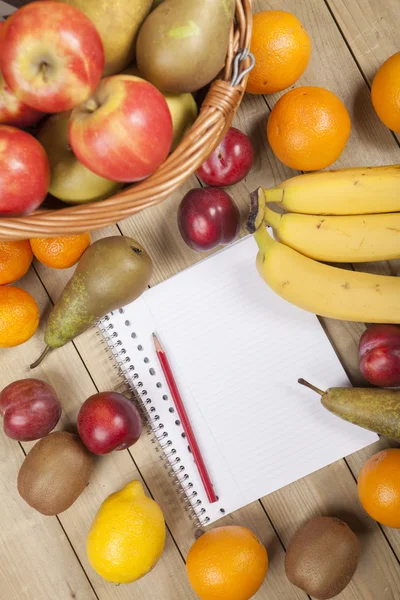 Frutas en cesta con lápiz y libro —  Fotos de Stock