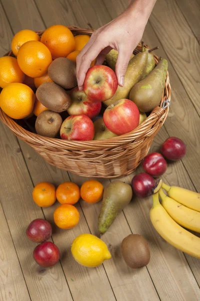 Hand picking up an apple from basket — Stock Photo, Image