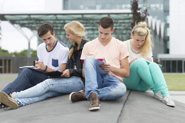 Cuatro estudiantes están aprendiendo sentados en el suelo —  Fotos de Stock