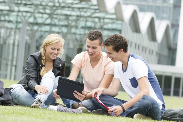 Drie studenten kijken naar een ipad — Stockfoto