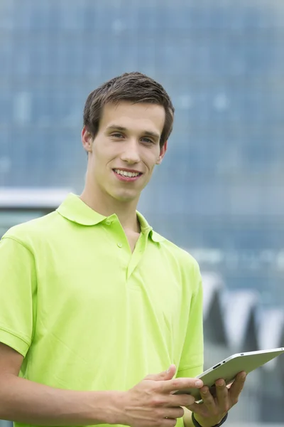 Ung student leende med sin ipad i handen — Stockfoto