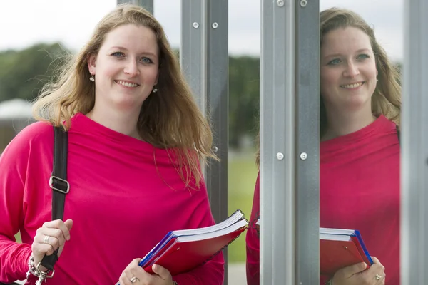 Student smiles with some books and a bag in her hands — Stock Photo, Image