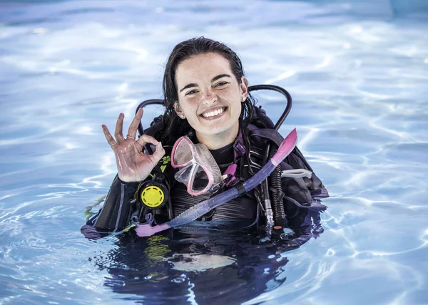 若いです女性とともにScubaギアでプールで笑顔でカメラショーをOkサイン — ストック写真